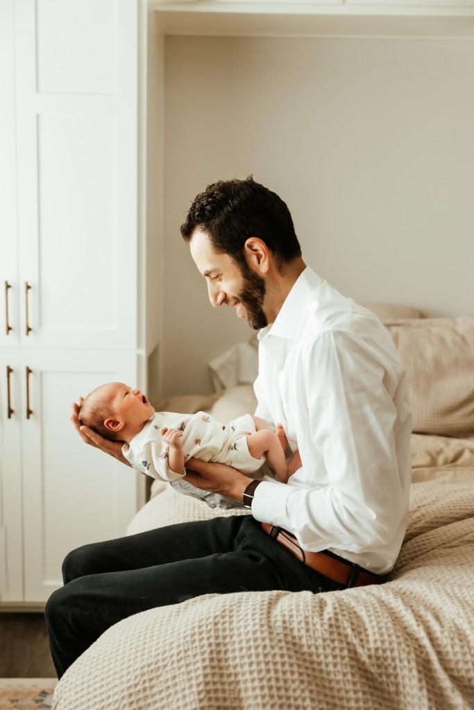 Father hold new baby in his arms, baby yawns.