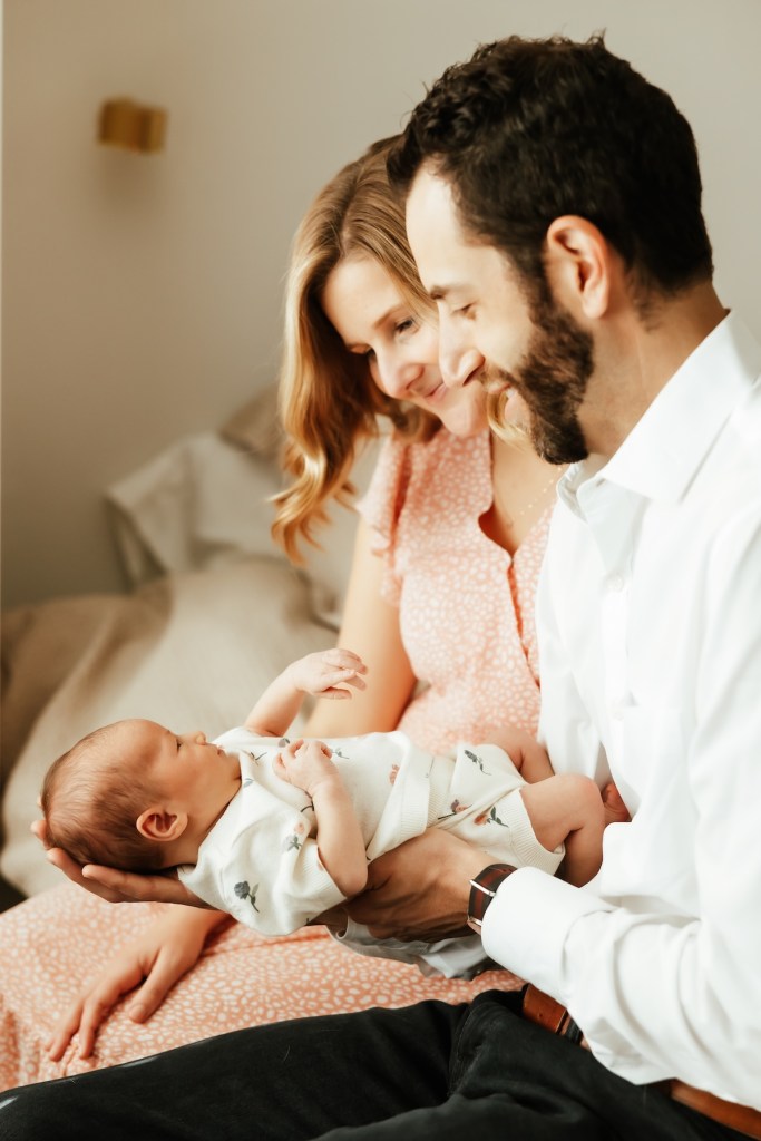 mother and father gaze lovingly at newborn baby.