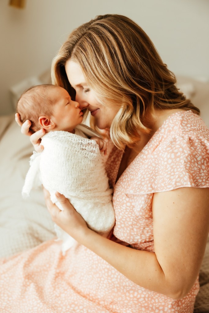 Mother nuzzles new baby's cheek with her nose.