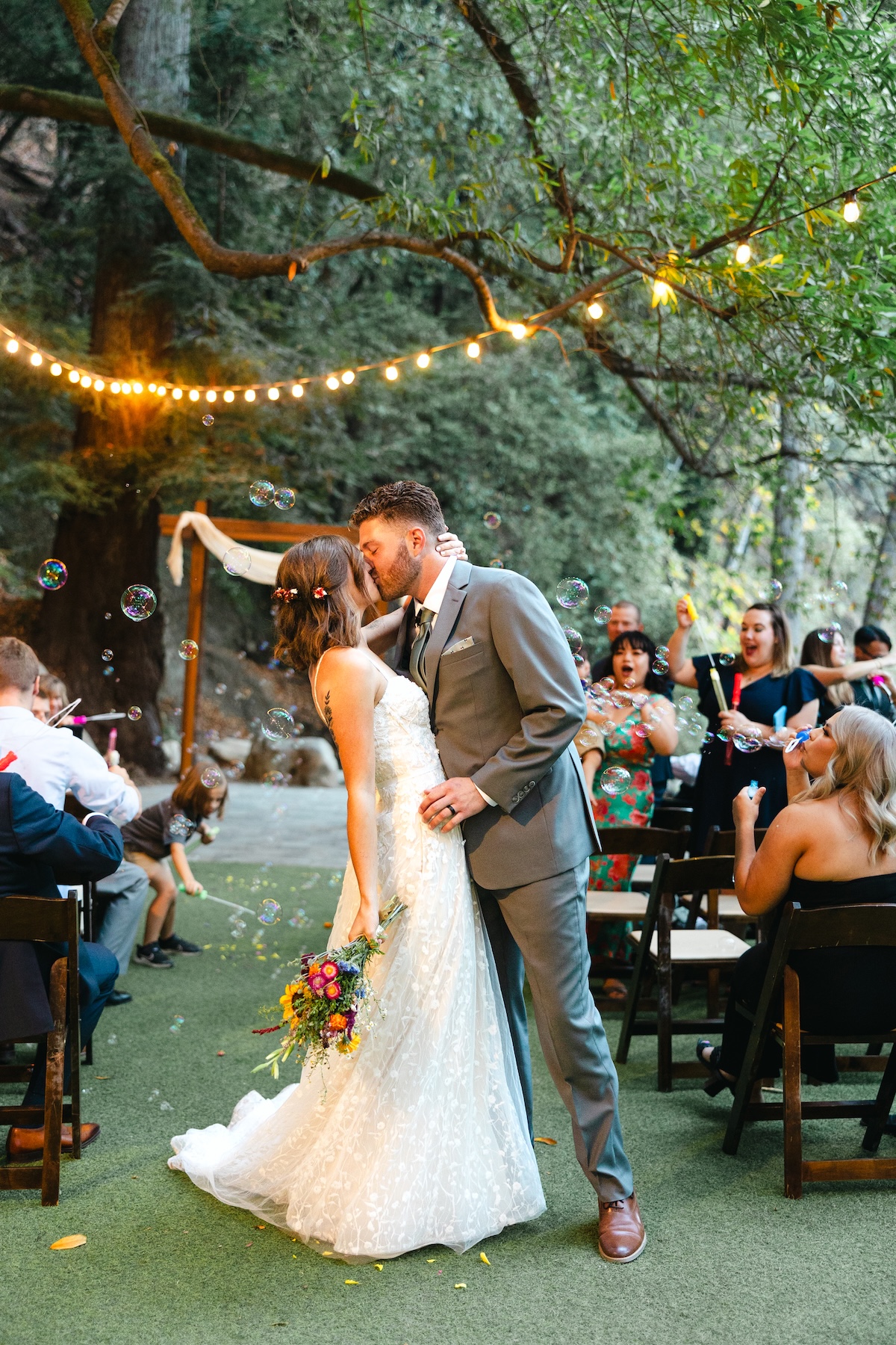A couple kisses at the end of their wedding ceremony at Redwood Grove, Saratoga Springs California.